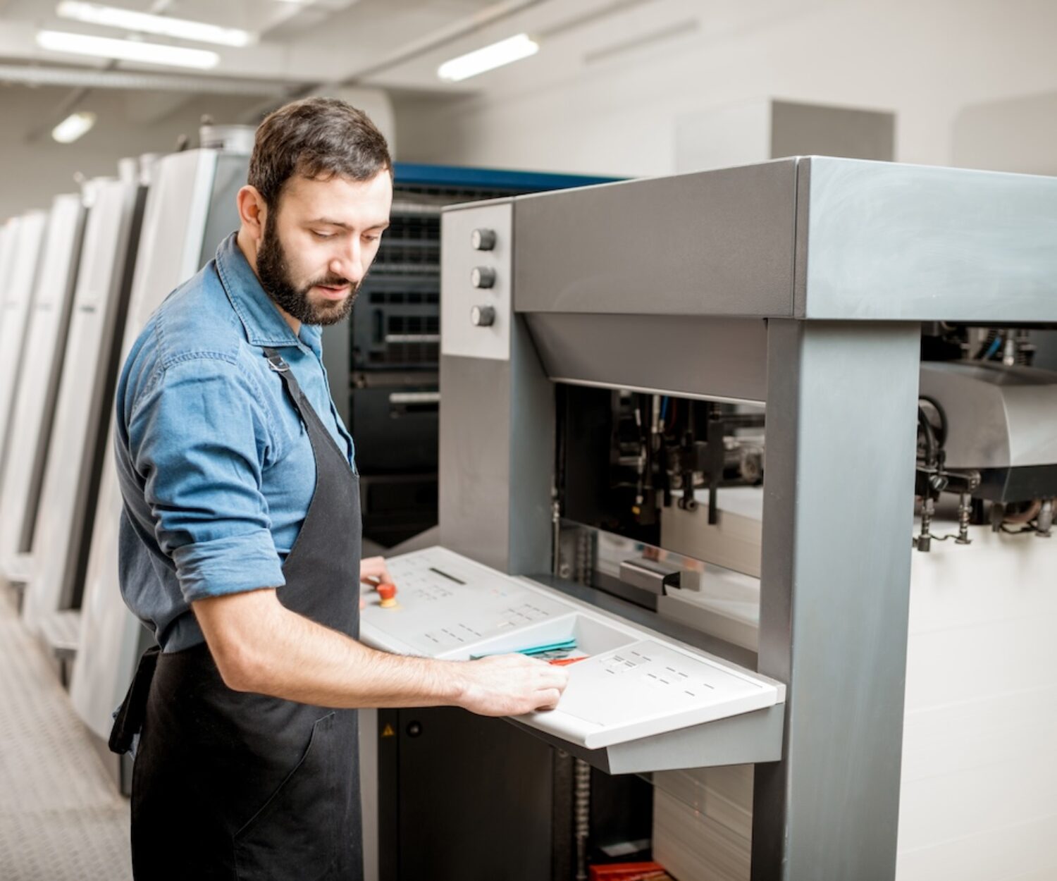 Printing operator working with offset machine at the printing manufacturing